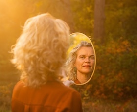 Afbeelding vrouw kijkt in spiegel